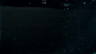 Siyah zemin üzerinde kabarcıklar ve parçacıklar olan şeffaf su dokusu