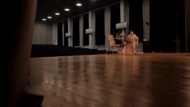 Çocuklar ahşap zemini olan büyük bir konser salonunda satranç oynarlar.