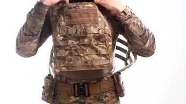 Kum rengi askeri üniformalı bir asker modern bir çelik yelek giyiyor. Beyaz arkaplan