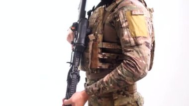 Kurşun geçirmez yeleği ve elinde çarpışma görüşü olan bir savaş tüfeğiyle askeri teçhizat uzmanı beyaz arka planda ekseninin etrafında dönüyor. İzole edilmiş