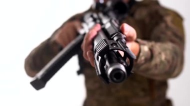 Özel bir askeri şirketten gelen paralı asker kameraya otomatik bir tüfek doğrultuyor. Beyaz arka plan. İzole edilmiş