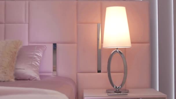 现代的彩色床头灯在一个奢华的卧室里 在一个时髦的床旁边 在早晨的阳光下 后续行动 — 图库视频影像