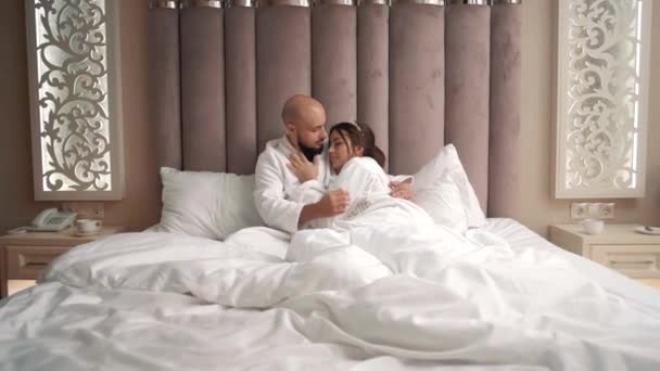 年轻英俊的男女穿着白衣躺在床上轻抚对方 — 图库视频影像