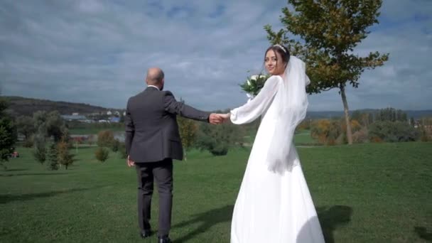 可爱的新娘正和未婚夫一起穿过一个整洁的自然公园 转过身去 — 图库视频影像