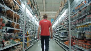 Büyük bir DIY ev geliştirme süpermarketinin inşaat malzemeleri bölümünün müdürü çalışırken sıra sıra ürünler arasında yürüyor
