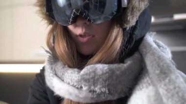 Snowboard yaparken gözlüklü tatlı bir kız sıcak örgü örüyor.