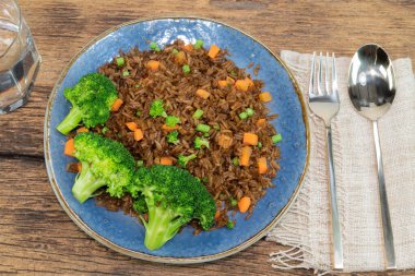 Kırmızı ahşap zemin üzerinde izole edilmiş brokoli soslu sebzeli pilav. Kaşık, üst görüş, yiyecek ve içecek kavramları var..