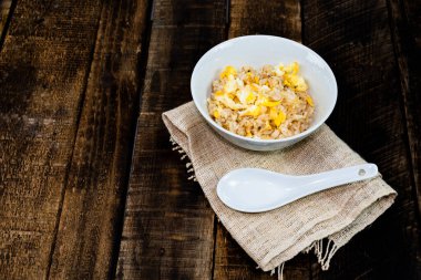 Kavanozda yumurta ile kızartılmış pirinç ahşap masa arkasına izole edilmiş kaşık yakın plan, üst görüş, kahvaltı yemeği ve içecek konsepti. 