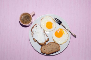 Tabakta kızarmış yumurta dilimi pembe arka planda izole edilmiş espresso kahvesi üst tarafta, kahvaltı ve içecek konsepti var..