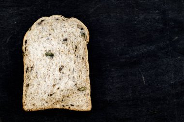 Tam buğday ekmeği dilimi, ahşap arka planda pirinç tanecikleri vardır. Yakın çekim, fotokopi alanı, kahvaltı yemeği ve içecek konsepti..