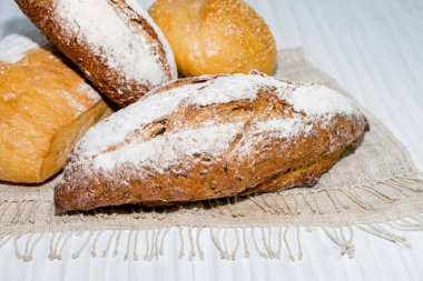 Beyaz ahşap arka planda izole edilmiş farklı ekmek yuvarlak baget, kırsal kabuklu üst görünüm, yiyecek ve içecek kavramı.