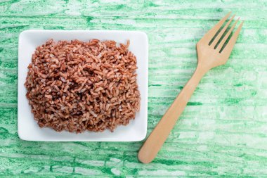 Yeşil arka planda yalıtılmış pirinç kırmızısı çatal, üst görüş, Asya yemeği ve içecek kavramına sahiptir..