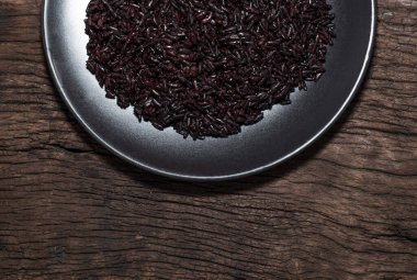 Tabaktaki siyah pirinç, ahşap arka planda izole edilmiş yemek çubukları fotokopi alanı yakın, üst manzara, sağlıklı yiyecek ve içecek konsepti var..