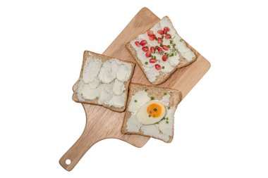Ekmek dilimi krem peynirle kaplanmış. Beyaz arka planda izole edilmiş kesme tahtasıyla haşlanmış yumurta. Üst manzara, kahvaltı yemeği konsepti..