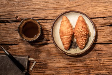 Siyah taş masadaki Espresso kahve ve kruvasan kitabın arka planında izole edilmiş. Yakın plan, üst görüş, kahvaltı ve içecek konsepti..