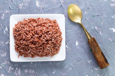 Mavi arka planda yalıtılmış pirinç kırmızısı kaşıkla kaplıdır, üst manzara, Asya yemekleri ve içecek konsepti vardır..