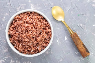 Mavi arka planda yalıtılmış pirinç kırmızısı kaşıkla kaplıdır, üst manzara, Asya yemekleri ve içecek konsepti vardır..