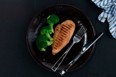 Siyah ahşap kaplama tabakta ızgara tavuk ve brokoli, sağlıklı yiyecek konsepti..