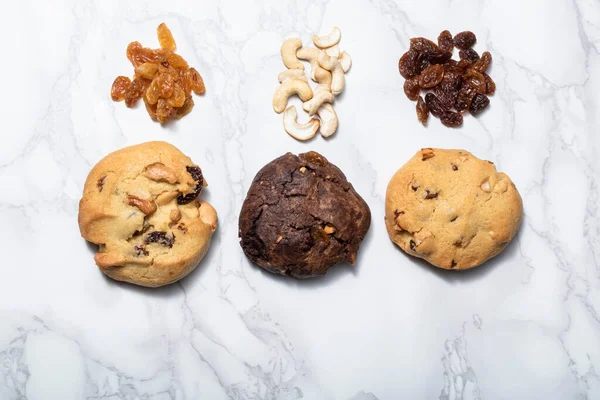 Cashew nuts raisin chocolate cookies on white marble background, close up, food and drink concept.