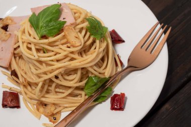 Beyaz tabakta kurutulmuş kırmızı biberli makarna, ahşap arka planda izole edilmiş. Üst manzara, yemek konsepti..