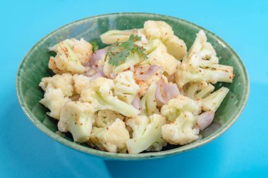 Mavi arka planda karnabahar salatası yakın plan, üst görüş, sağlıklı gıda konsepti.