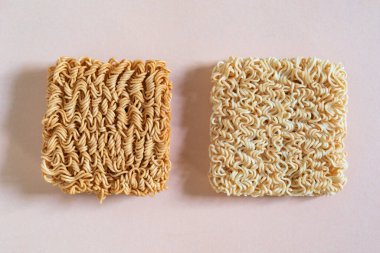 İzole edilmiş pembe ahşap arka planda sarı hazır şehriye, üst manzara, Asya yemekleri konsepti..