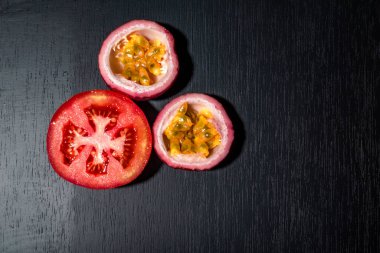 Domates diliminin siyah ahşap arka planda çarkıfelek meyvesi var..