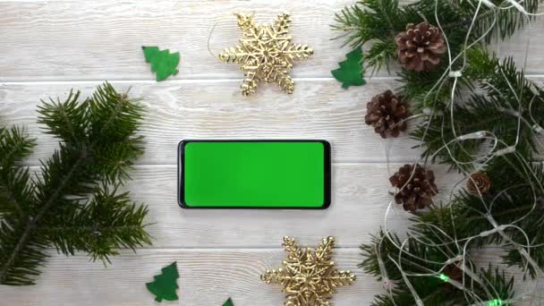 緑の画面技術クリスマスの装飾テーブルの上に携帯電話フラットレイ,コピースペーステキストのためのモックアップ,スマートフォンクロマキー,新年オンラインコンセプトいいえ人々 — ストック動画