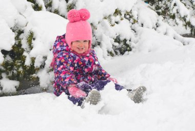 Kışın giydiği beyaz çocuk dışarıda oynuyor.