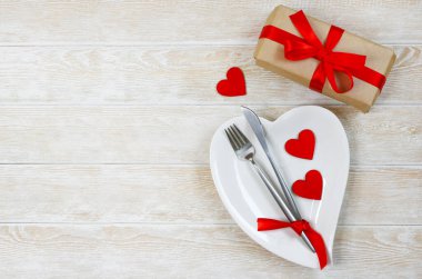 Sevgililer günü masası düzleştiriliyor beyaz seramik tabaklar şeklinde kalp, şenlikli dekorasyon, çatal ve bıçak ve kırmızı çevre dostu sıfır atık kutusu uzay metninin kopyası