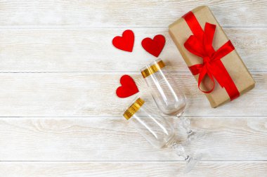 Sevgililer günü arkaplanı metin için fotokopi alanı, kırmızı kurdeleli bayram hediyesi kutusu ve ahşap süslemeler kalp şekli, şarap veya şampanya için bir bardak.