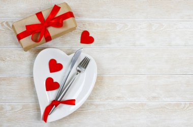 Sevgililer günü masası düzleştiriliyor beyaz seramik tabaklar şeklinde kalp, şenlikli dekorasyon, çatal ve bıçak ve kırmızı çevre dostu sıfır atık kutusu uzay metninin kopyası.