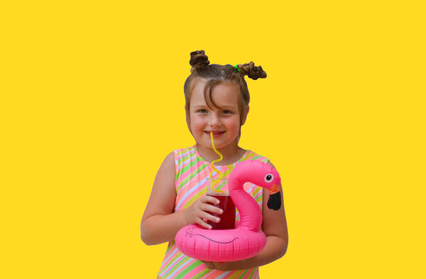 portrait happy caucasian child girl drinking fresh juice with inflatable flamingo in summer.