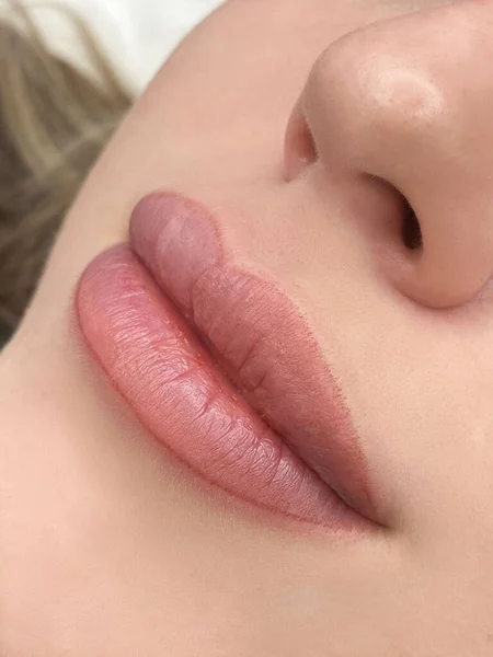 Permanente make-up op de lippen van een jonge vrouw van een delicate perzik schaduw close-up, een meisje na een cosmetische ingreep met een gladde en schone gezonde huid — Stockfoto