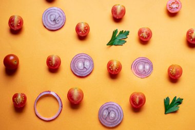 Turuncu bir arka planda domates kirazı ve soğan.