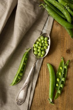 Masada taze bezelye ve bir parça önlükle ahşap kaşık