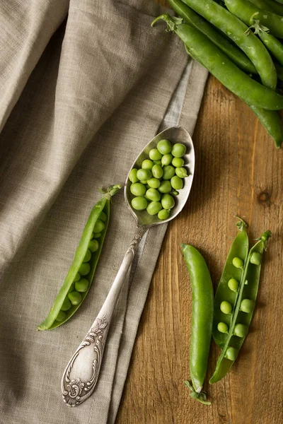 Masada taze bezelye ve bir parça önlükle ahşap kaşık