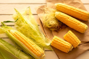 Beyaz ahşap bir masada taze sulu çiğ mısır. Yazın kokusu. Yukarıdan görüntüle
