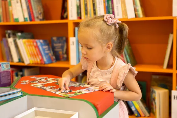 Una Niña Linda Rosa Recoge Rompecabezas Biblioteca Mira Marco —  Fotos de Stock