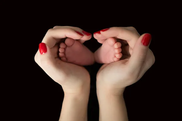 这张新生的小脚的照片握在妈妈的手中 在黑色的背景上呈心形 妻子阵线 — 图库照片