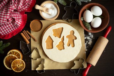 Pişirme malzemeleriyle mutfak Noel arkaplanı - podyumda yuvarlak hamur, kurabiye keskisi, merdane, şeker, yumurta, kurutulmuş portakal, iki çeşit tarçın, parşömen, apron. Düz yatıyordu