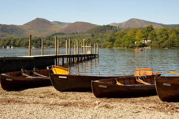 Shore of a lake with a wooden jetty and wooden boats, Lake District, England. Summer early