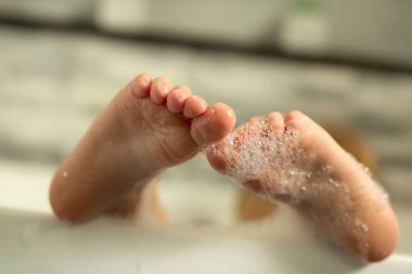 Uzun bir banyodan sonra küvette köpüklü şirin bebek ayakları. Seçici odak.