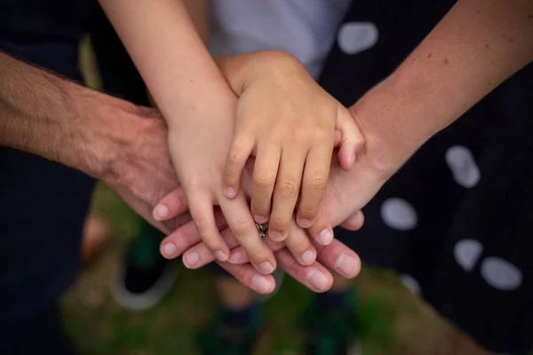 A pyramid of family hands - parents and two children. Concept of family unity, friendship, values, support. Selective focus. Green background blue clothes