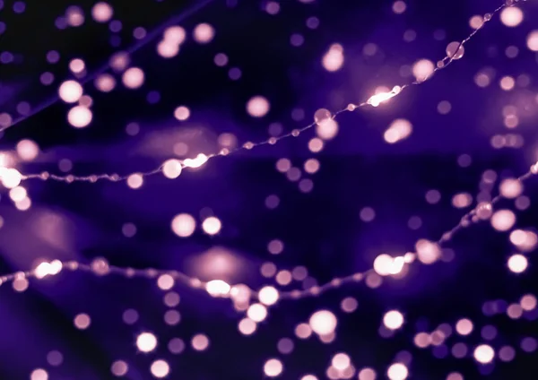 Bokeh en feestelijke verlichting op violette achtergrond. — Stockfoto
