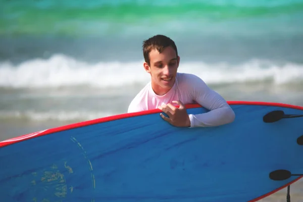 Teenager holding blue surfboard near the sea — Φωτογραφία Αρχείου