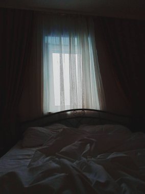 Buruşmuş beyaz battaniyeli düz bir yatak.