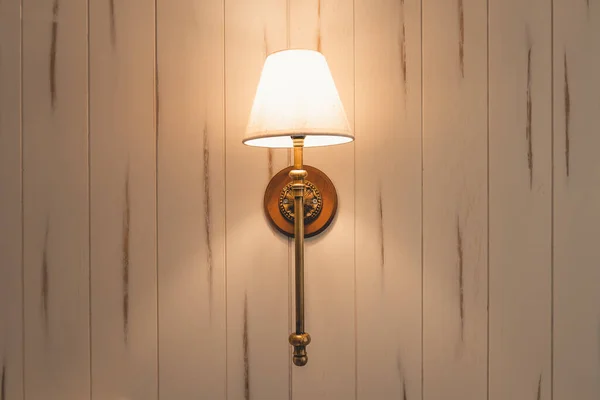 Wall lamp on wooden wall with warm light in the bedroom.