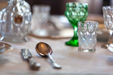 Çok eski bir kristal yemek seti maun bir yemek masasında sabahın erken saatlerinde açık bir pencerenin yanında.