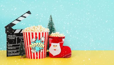 Patlamış mısır, Noel süsü, kar taneleri ve sarı ve mavi arkaplan üzerine yazı yazmak için alan içeren bir film tahtası. Noel filmleri konsepti